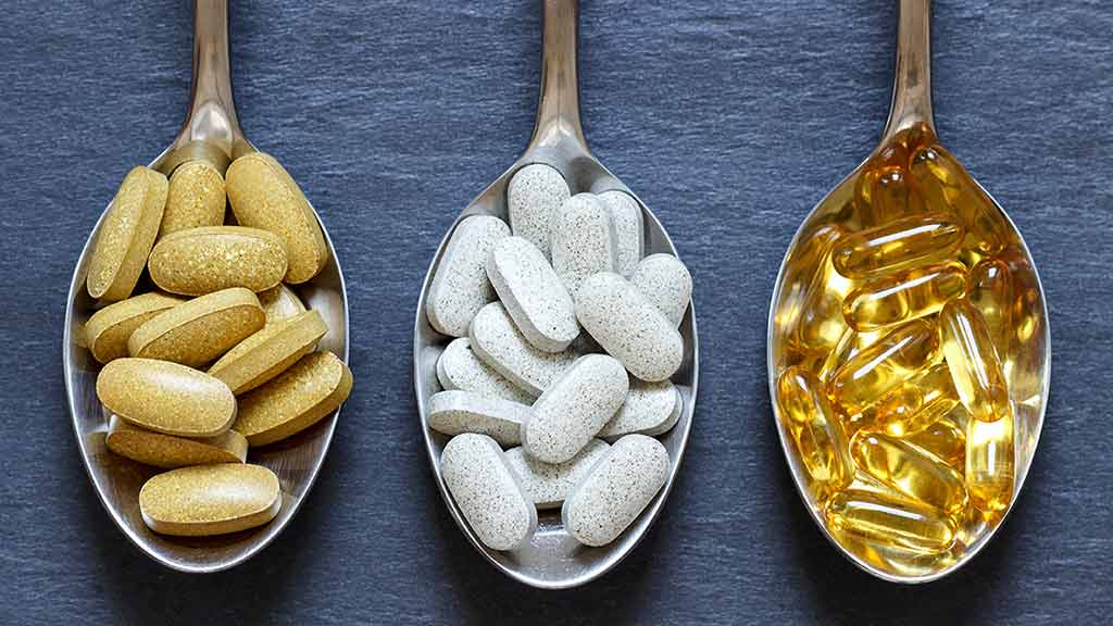 spoons of supplements on dark background