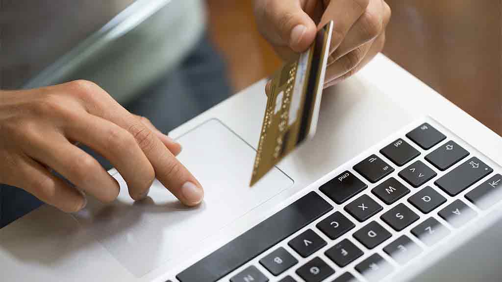 person holds credit card over keyboard