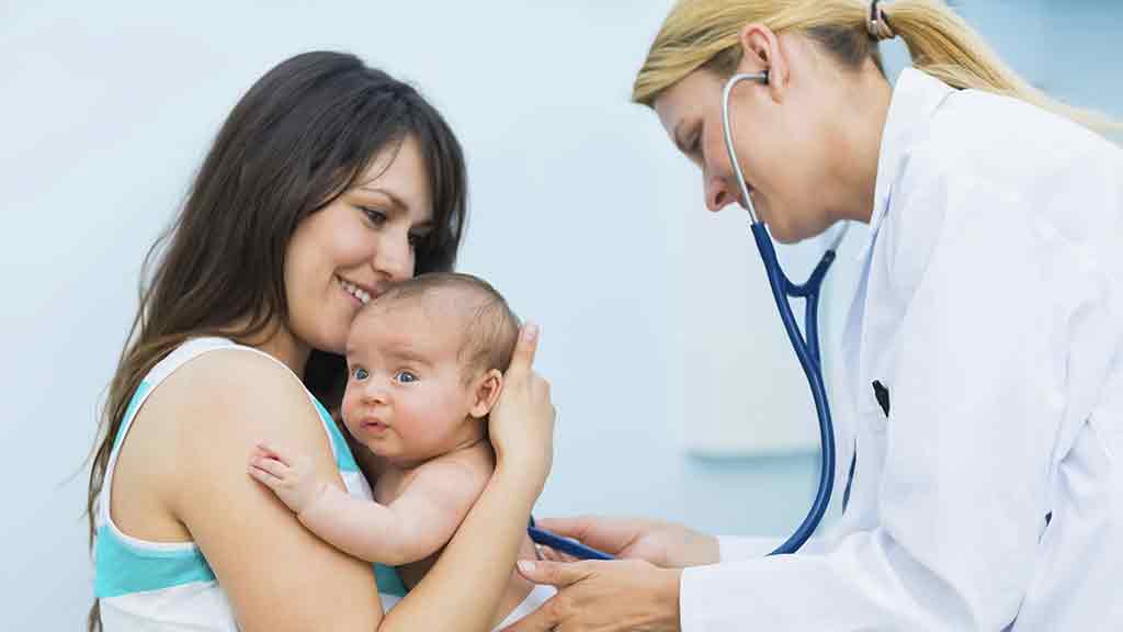 mother holds baby while nurse listens to hear beat