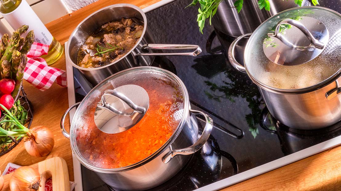 sauce pans with food cooking on stove