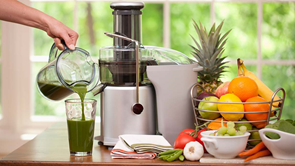 woman using juicer to make green juice