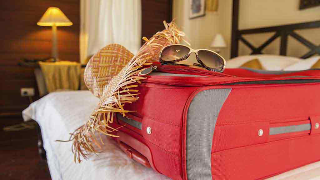 suitcase hat sunglasses on bed